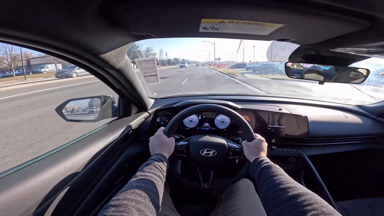 Clear centered driver's-eye interior view of the 2026 Hyundai Elantra N-Line showing both hands on the wheel, digital instrument cluster and road ahead.
