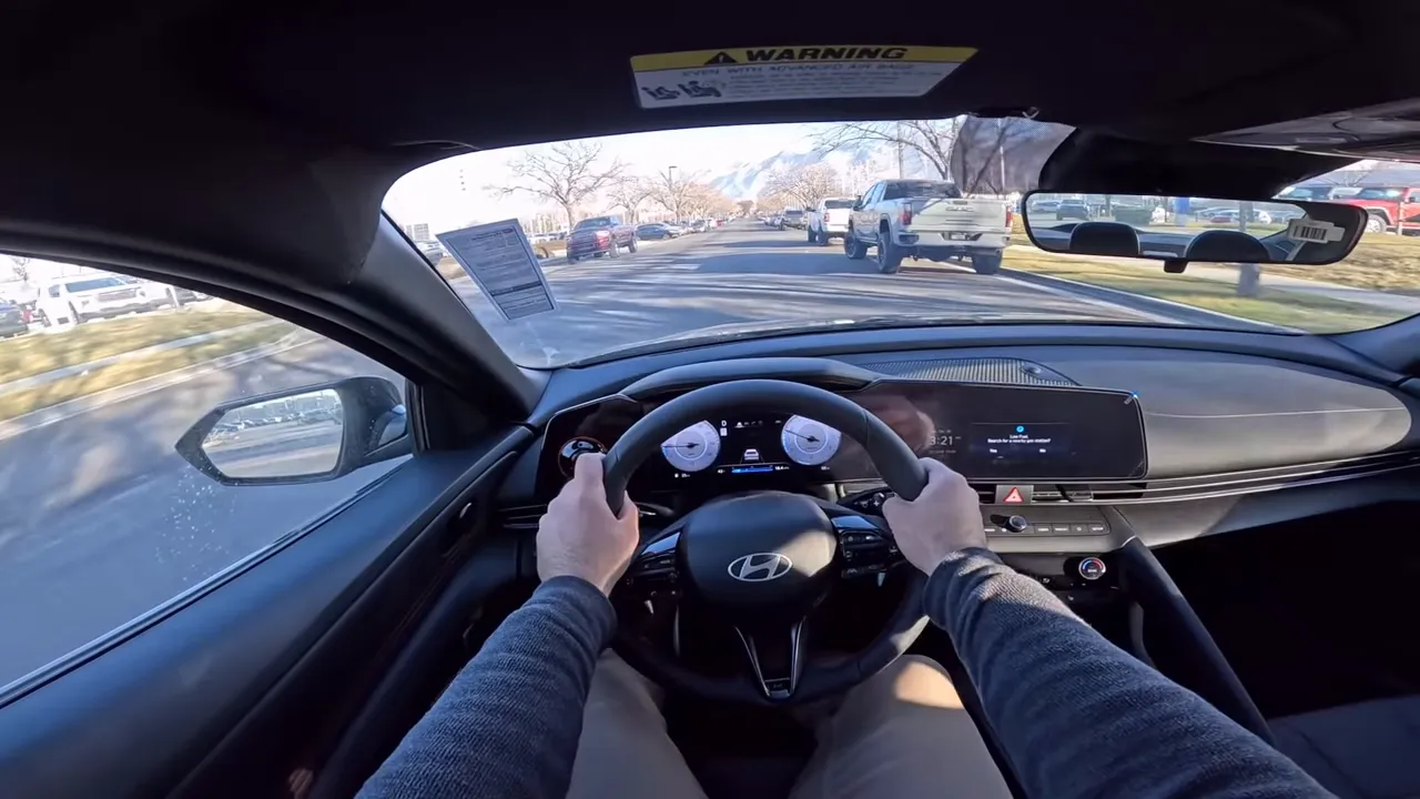 Centered driver's-eye view of the 2026 Hyundai Elantra N-Line interior showing the steering wheel, symmetrical digital instrument cluster, wide center display and the road ahead.