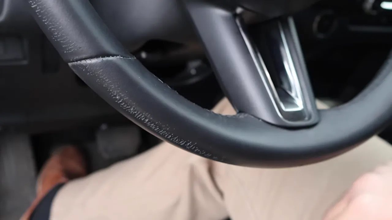 Clear close-up of the lower steering wheel rim showing flaking and pitting of the synthetic material on a Mazda CX-50.