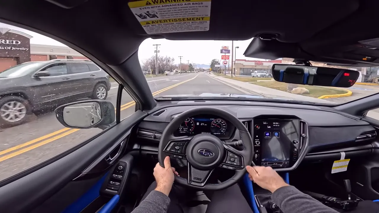 Point-of-view driving shot of Subaru WRX TS showing the steering wheel at 9-and-3, digital gauges and the road ahead.