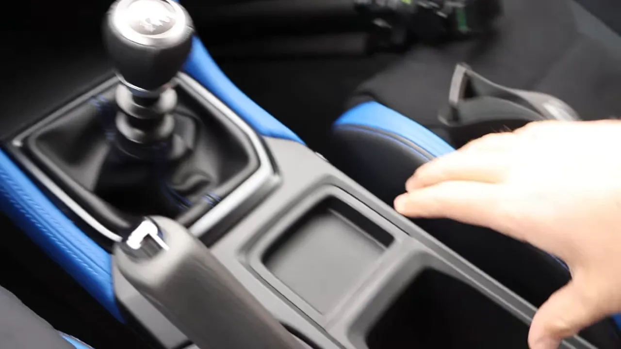 Six-speed manual shifter and center console of Subaru WRX TS showing gear knob, cup tray and blue trim