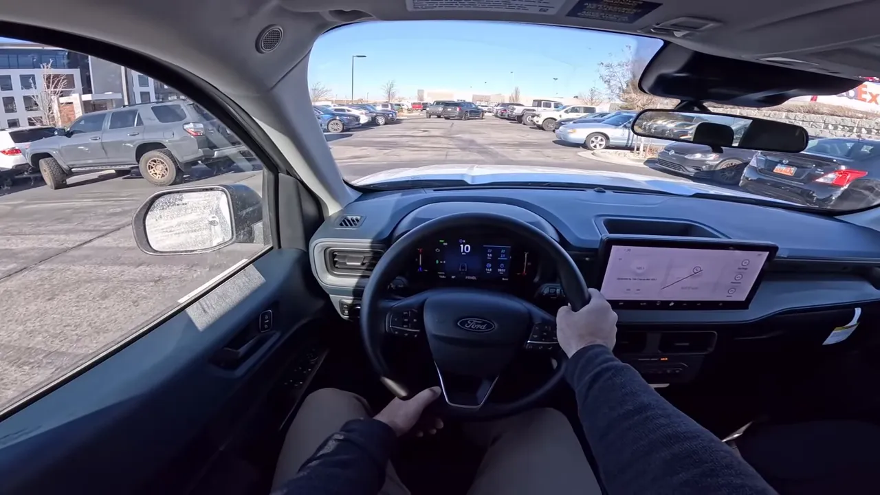 Front driver viewpoint of Ford Maverick interior showing steering wheel, instrument cluster, infotainment screen and roadway ahead