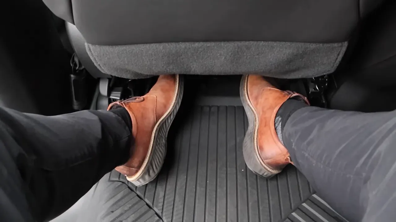 Wide view of the rear footwell and floor mat showing passenger legroom and seatback in the back seat.