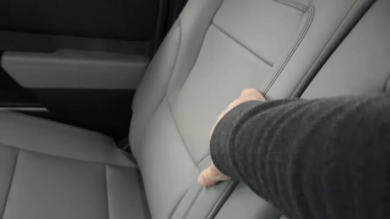 hand pressing leather rear seat to demonstrate cushioning and stitching