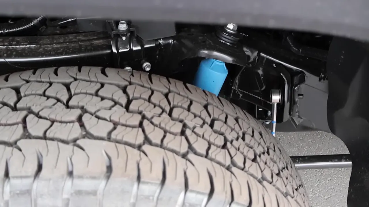Close-up of Toyota Tacoma rear suspension showing blue Bilstein shock and tire tread
