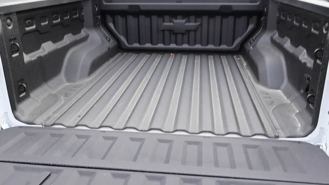 wide view into truck bed showing spray-in liner, tie-downs, and tailgate