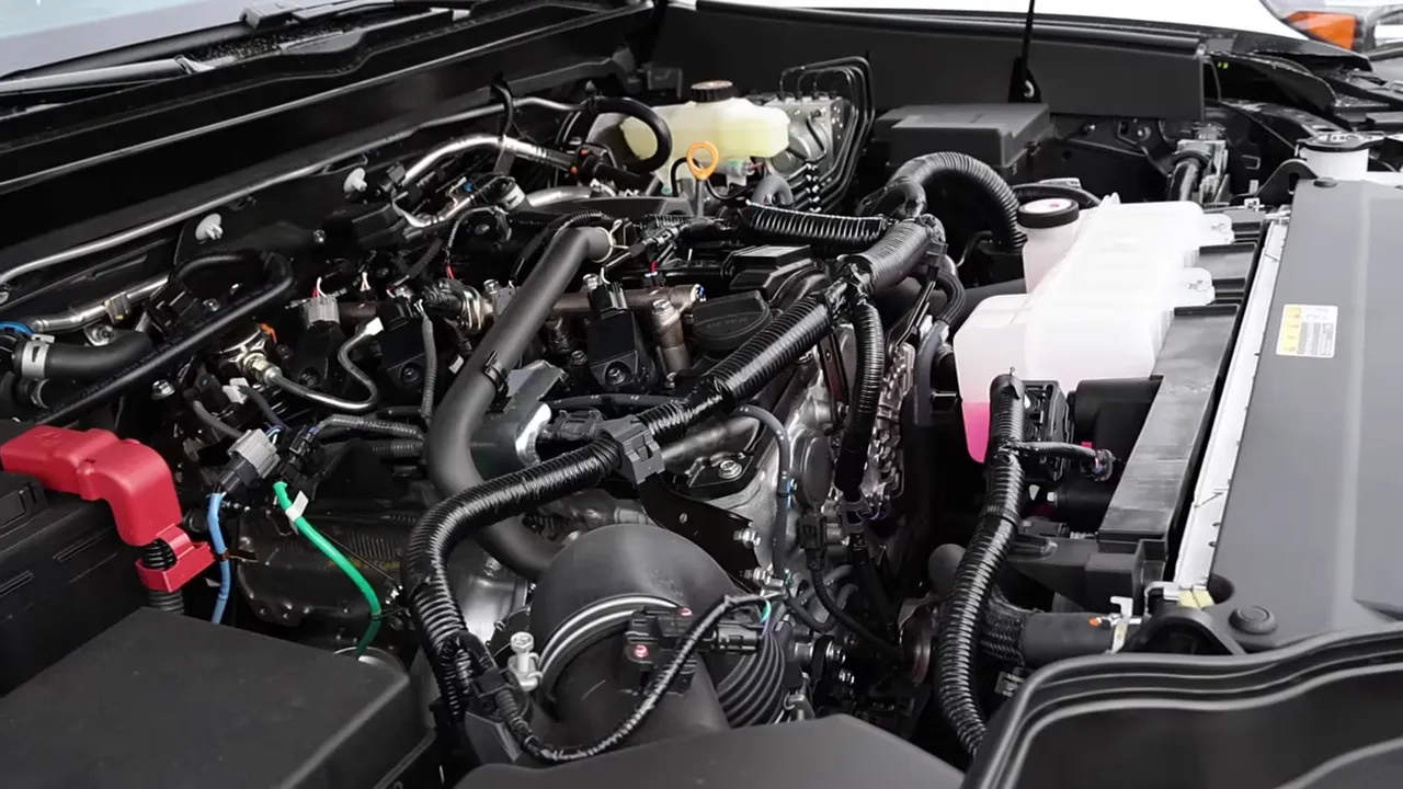 Close-up of the Toyota Tacoma engine bay highlighting turbo intake plumbing, wiring harnesses and coolant reservoir.