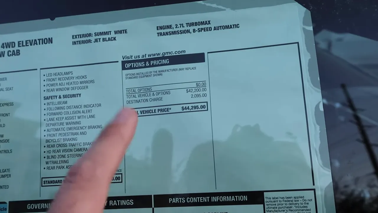 GMC Canyon window sticker with finger pointing at total vehicle price $44,295