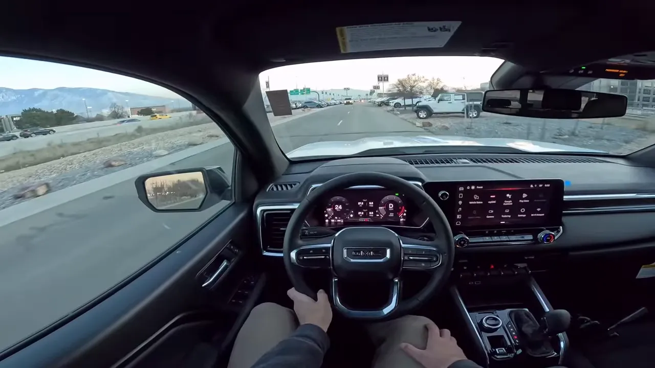 Balanced interior driver view of GMC Canyon showing steering wheel, digital gauges, center touchscreen and clear road ahead