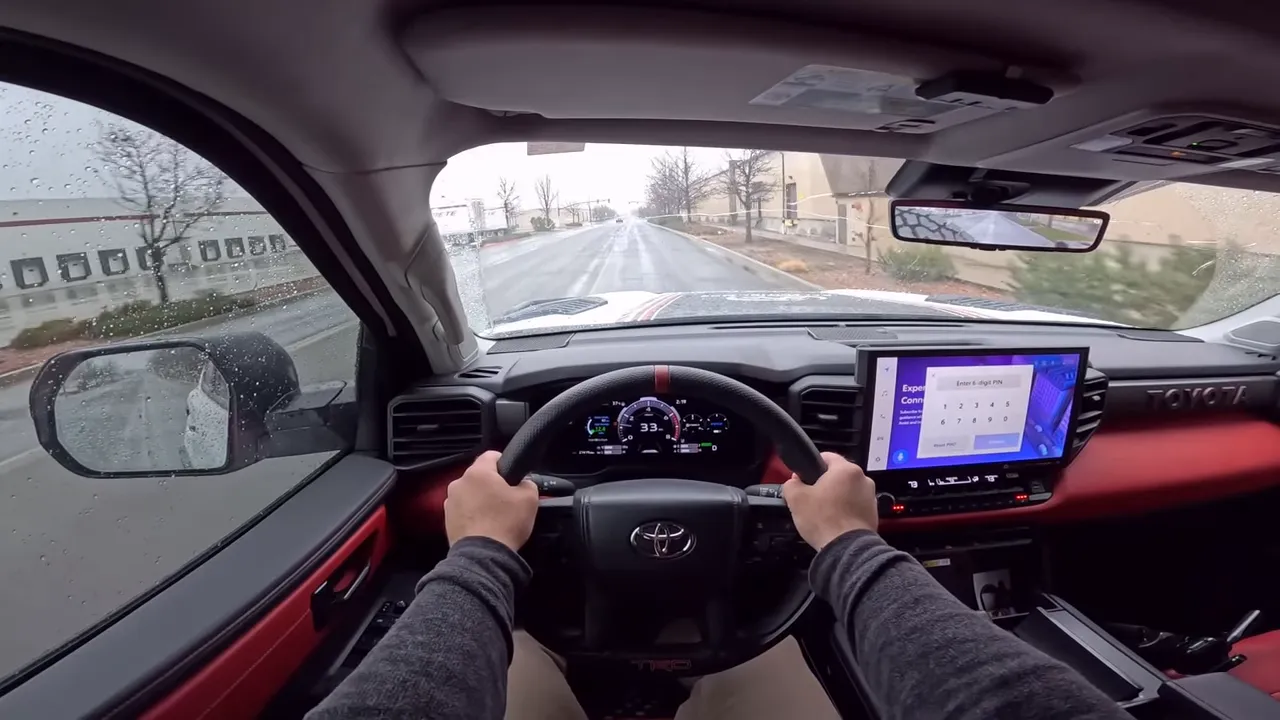 High-quality interior driver view of the Expedition One Toyota Sequoia with both hands on the wheel, clear instrument cluster and wet road ahead.
