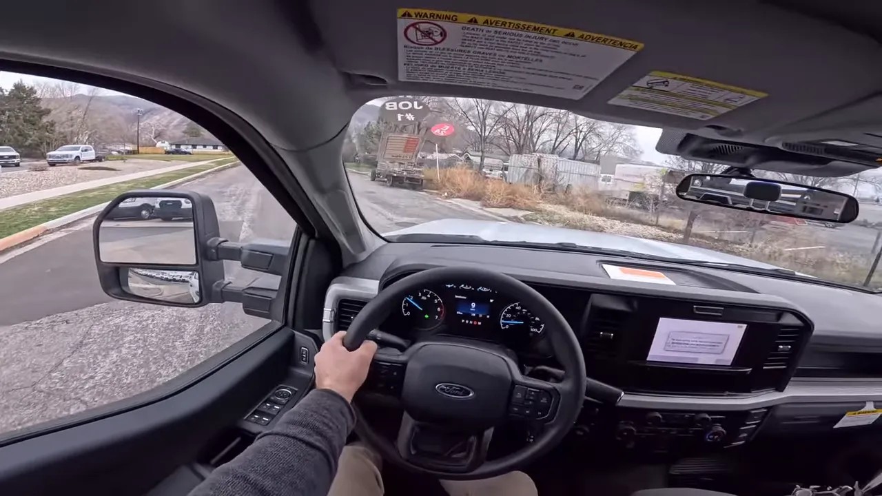 Driver viewpoint interior of 2026 Ford F-250 showing steering wheel, instrument cluster and center screen