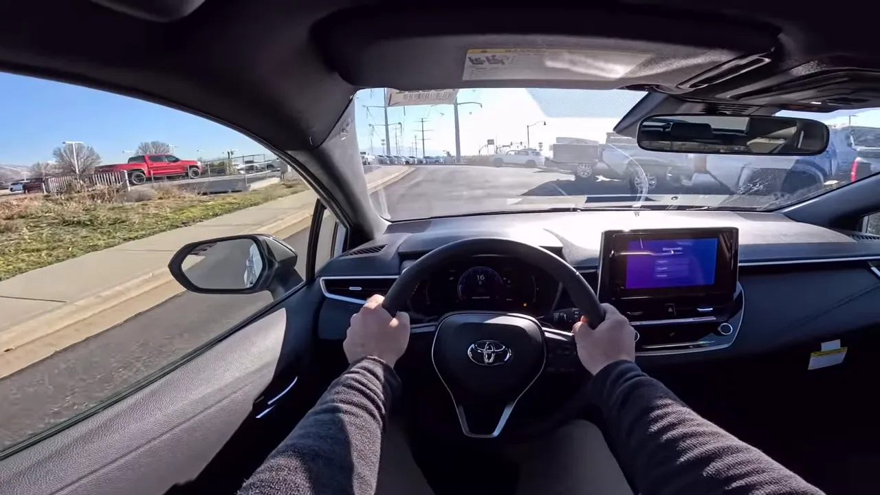 Driver POV in a 2026 Toyota Corolla showing both hands on the steering wheel, center display and a clear road view ahead