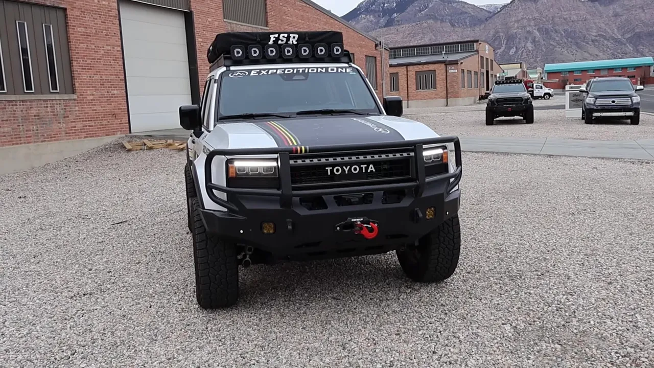 Front-facing shot of Expedition One Land Cruiser with integrated steel bumper, lights and red winch hook