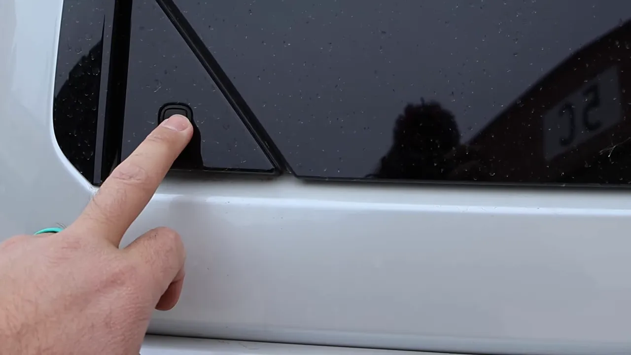 finger pressing the rear window pop latch on the Land Cruiser swing gate