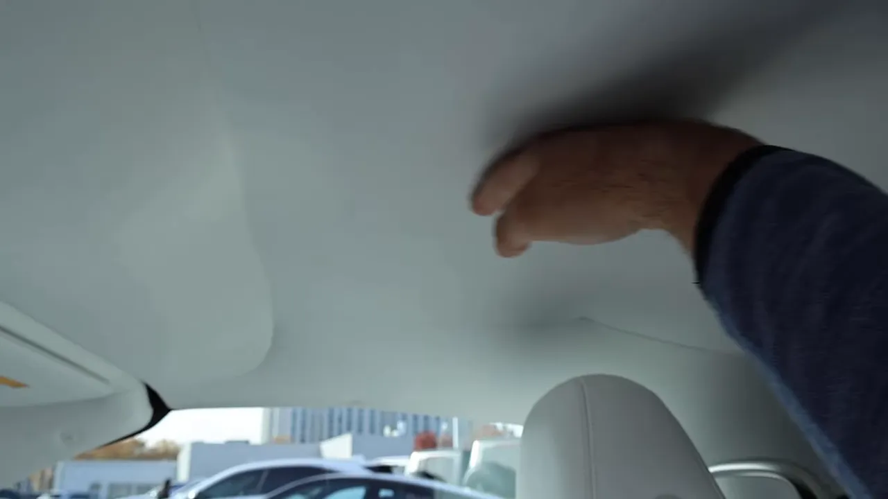 Hand pressing the Maybach SL680 convertible soft-top fabric from inside, showing material texture and light-colored headliner.