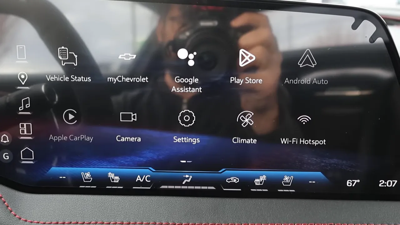 Corvette Z06 touchscreen home screen with icons for Vehicle Status, myChevrolet, Google Assistant, Play Store, Apple CarPlay, Camera, Settings and Climate; no hands in frame.