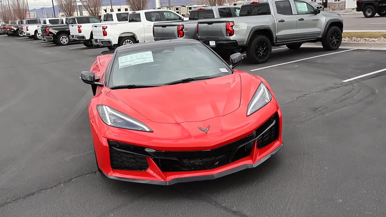 Front three-quarter view of a red 2026 Chevrolet Corvette Z06 showing the angular headlights, prominent front splitter, and aggressive styling.
