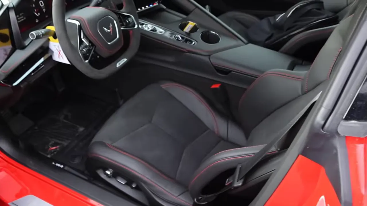 2026 Corvette Z06 interior view showing driver seat, steering wheel, center console and red stitching