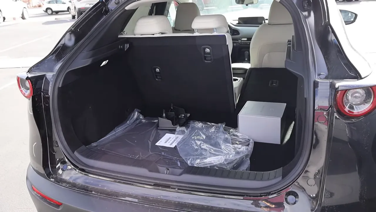 Open rear cargo of a compact crossover with one rear seat folded flat, showing trunk shape and a small box