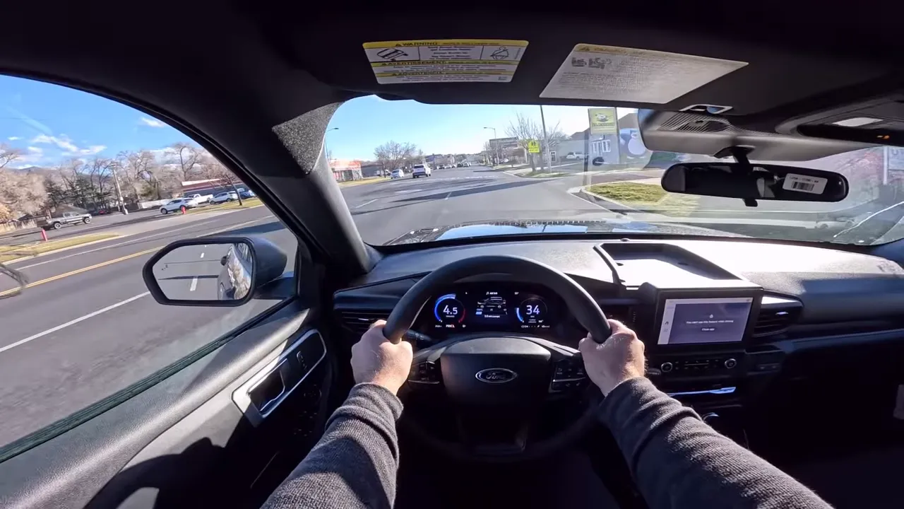 Driver perspective showing steering wheel and digital gauge cluster indicating 34 mph during a dynamic drive in the 2026 Ford Explorer Interceptor