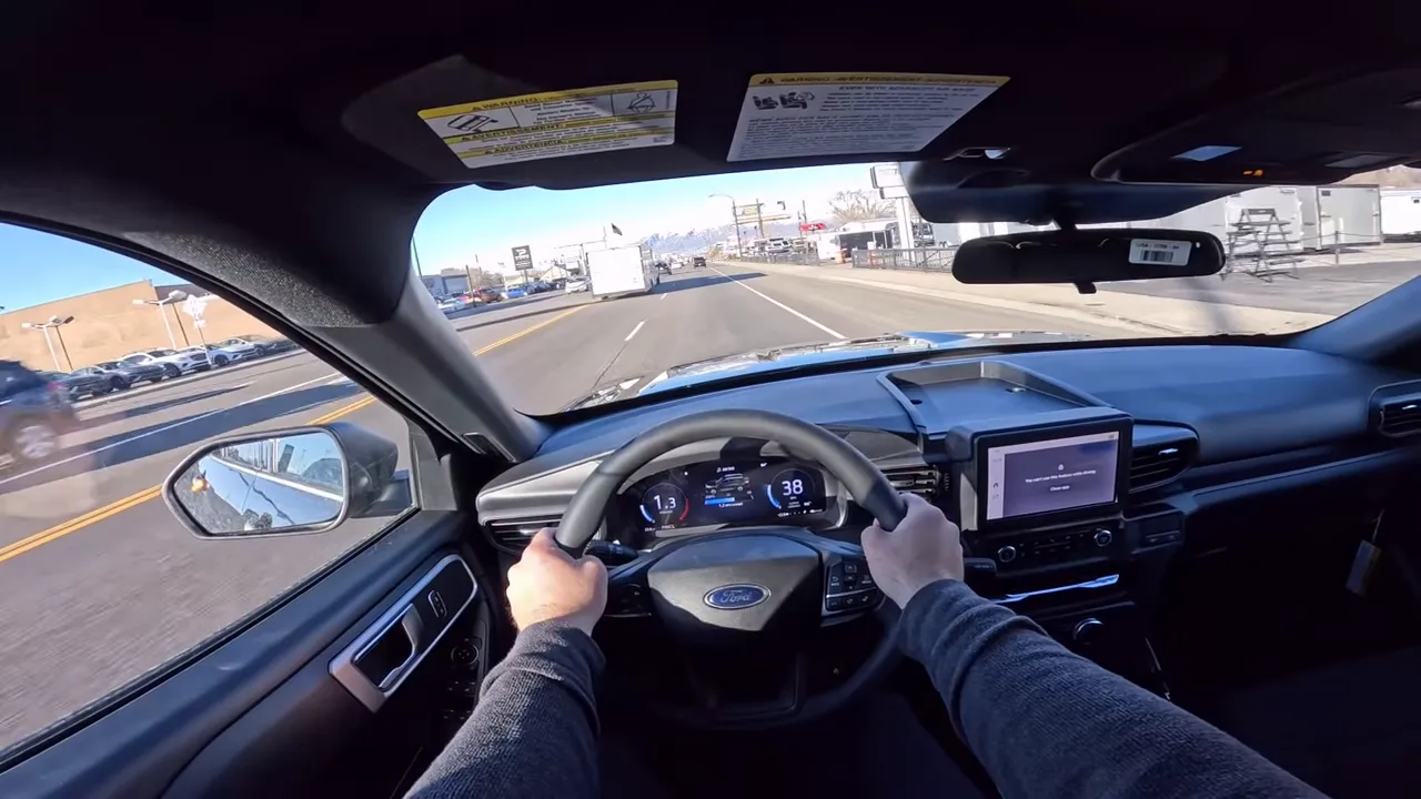Well-lit driver perspective of the Interceptor showing steering wheel, digital gauge cluster (38 mph) and infotainment touchscreen with physical knobs