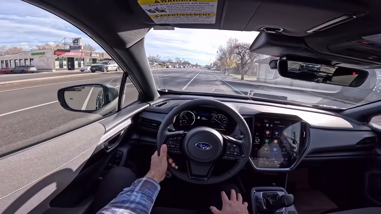 Clear interior view from the driver's seat of a Subaru showing steering wheel, digital instrument cluster with EV/eco display, center infotainment screen and road ahead.