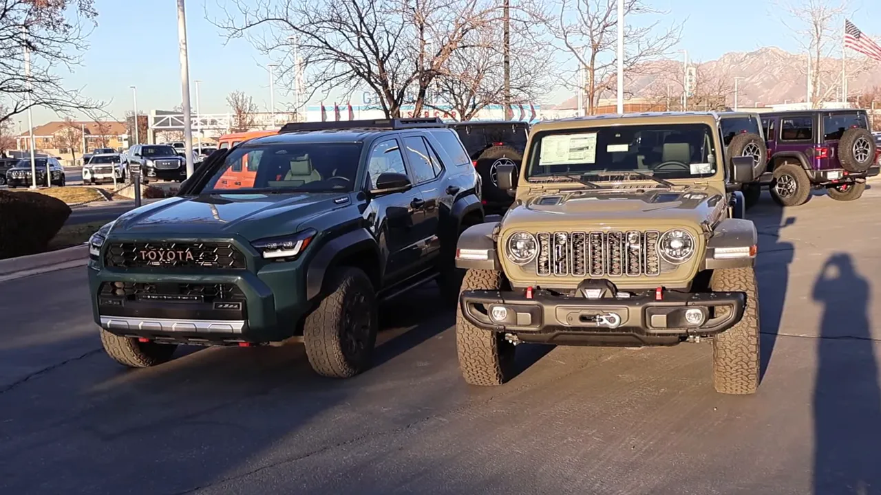 Front three‑quarter view of a 2026 Toyota 4Runner Trailhunter parked next to a 2026 Jeep Wrangler Rubicon in a dealership lot