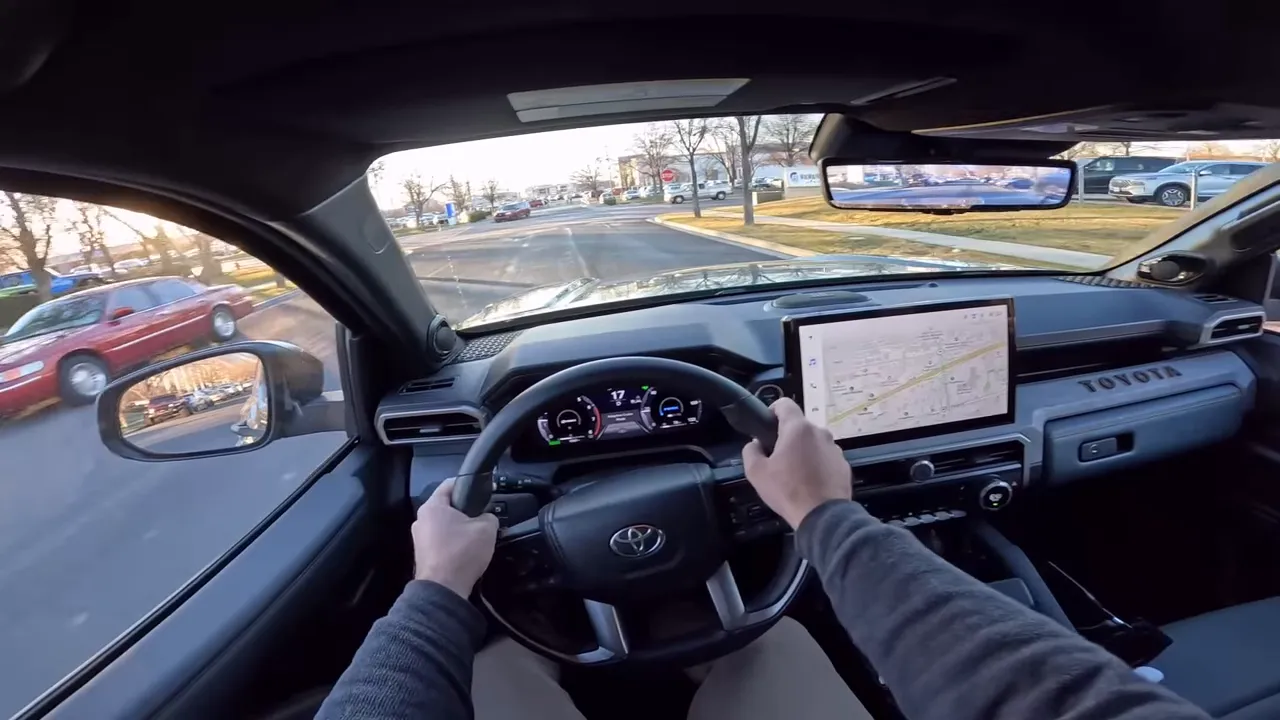 Two-hand driver POV inside a Toyota 4Runner Trailhunter showing the steering wheel, digital instrument cluster, infotainment navigation map and the road ahead