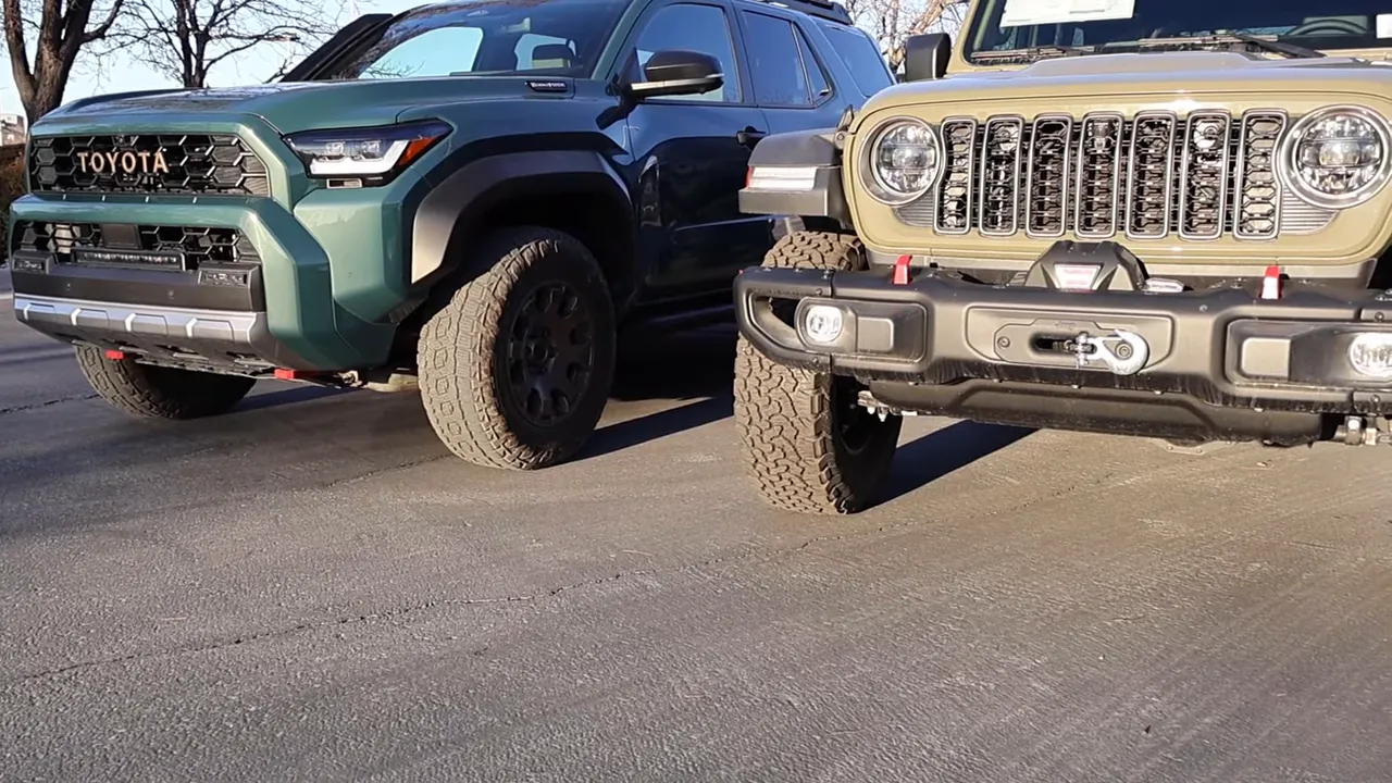Close front-end comparison of a 2026 Toyota 4Runner Trailhunter and a 2026 Jeep Wrangler Rubicon showing bumpers, grille, and recovery points