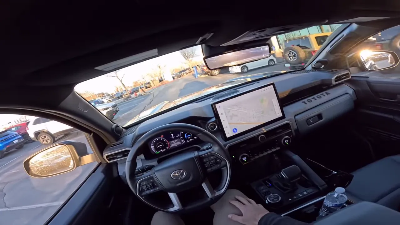 Driver POV inside a 2026 Toyota 4Runner Trailhunter showing the digital instrument cluster and the large infotainment screen displaying a navigation map.