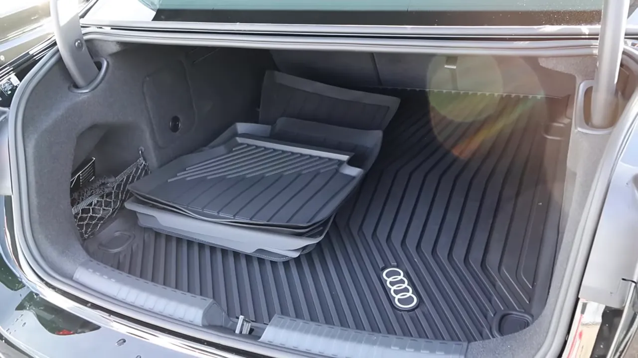 Open trunk of 2026 Audi A6 showing cargo mat, trunk floor pattern, and storage net