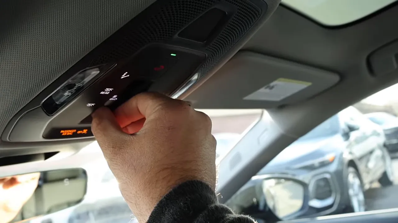 Hand pressing Audi A6 overhead control panel to toggle sunroof opacity