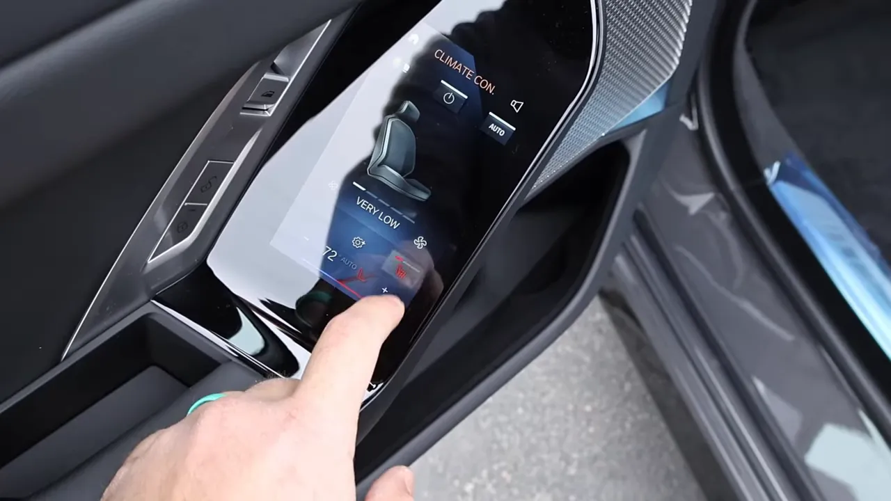 finger interacting with BMW rear door tablet control showing seat and climate options