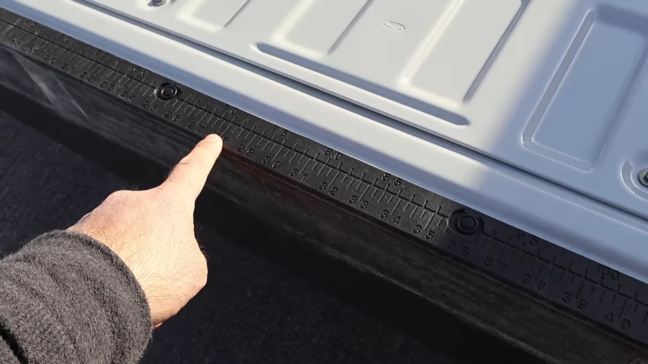 Close-up of tailgate edge ruler with finger pointing at measurements