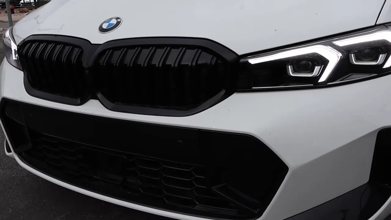 Front view of 2026 BMW 330i showing black grille, LED headlights and lower bumper intake