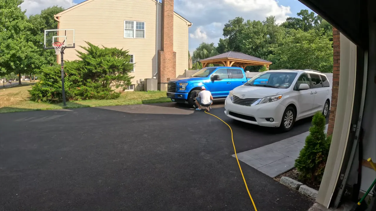 truck tire being inflated with a yellow air hose connected to a blue pickup on a driveway