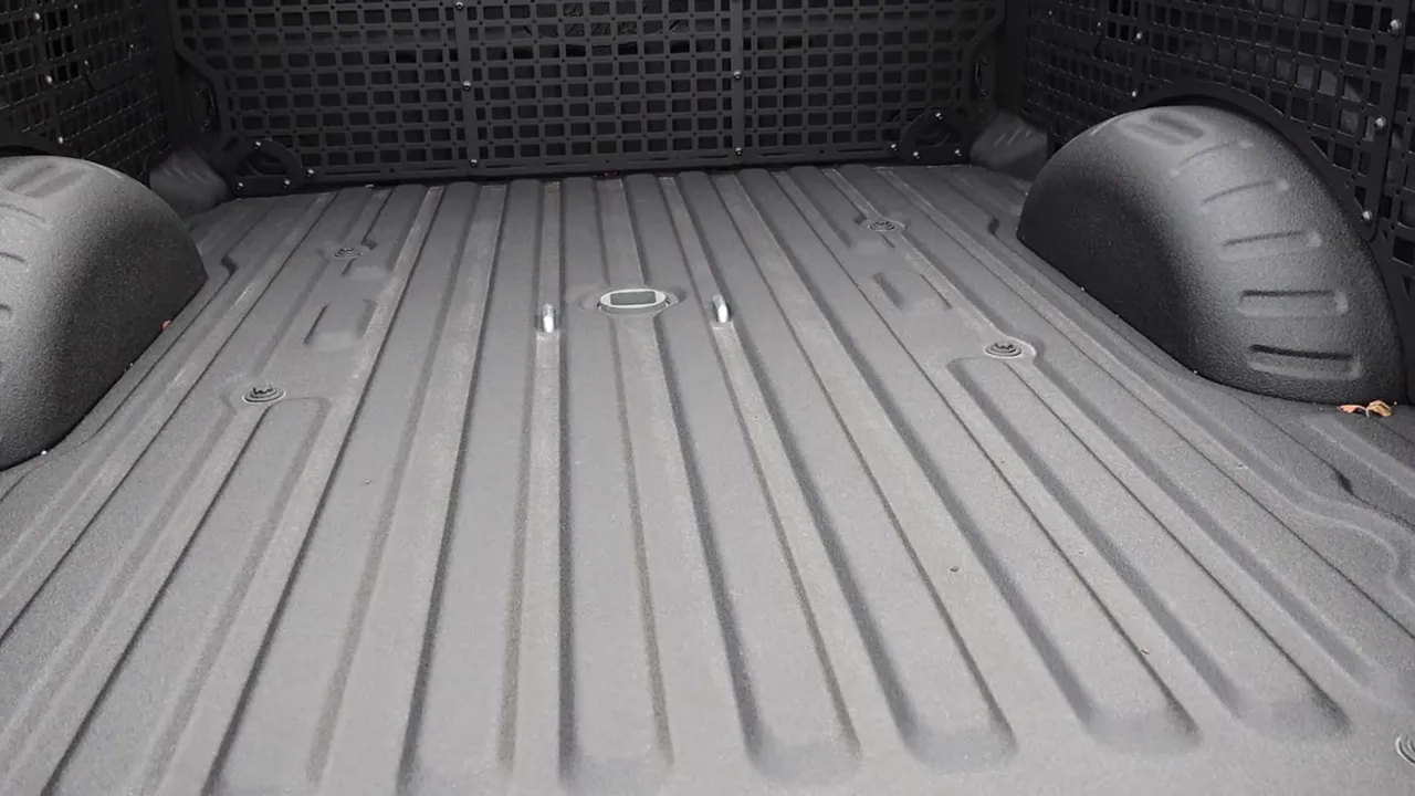 Truck bed showing built‑in gooseneck pocket, tie‑downs and wheel wells with spray‑in liner