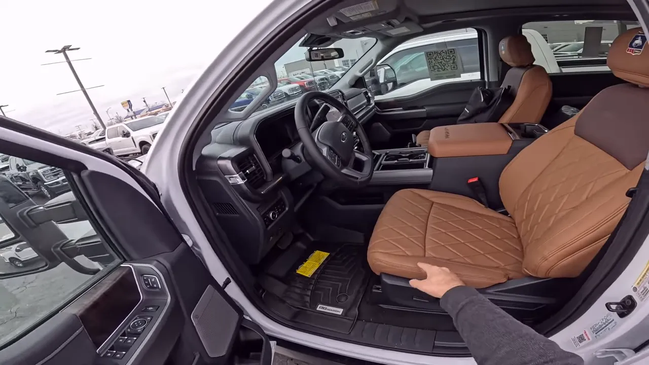 Wide driver-side interior view showing steering wheel, dashboard, center console and brown quilted seats