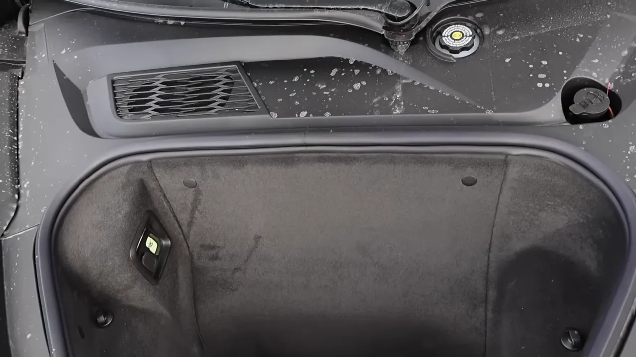 Top-down view of Corvette frunk showing carpeted lining, front vent and filler cap