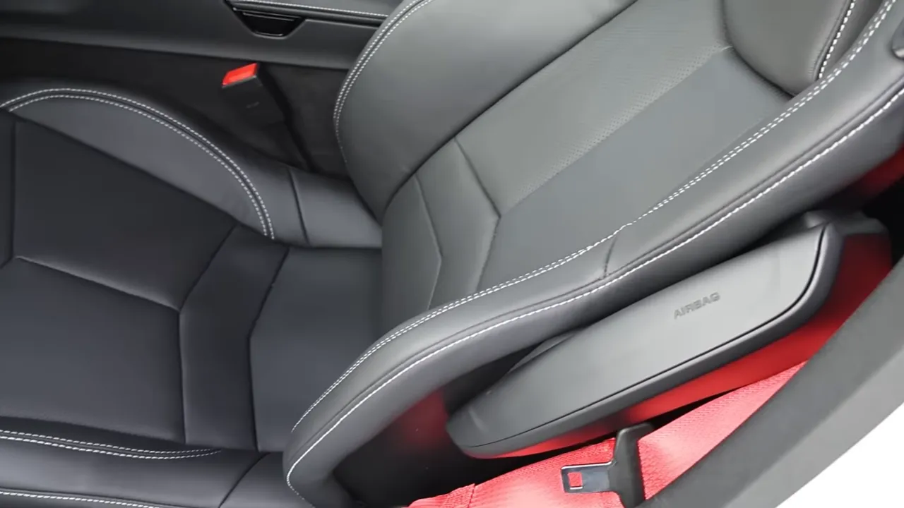 Corvette bucket seat showing perforation, bolstering, contrast stitching and red seatbelt