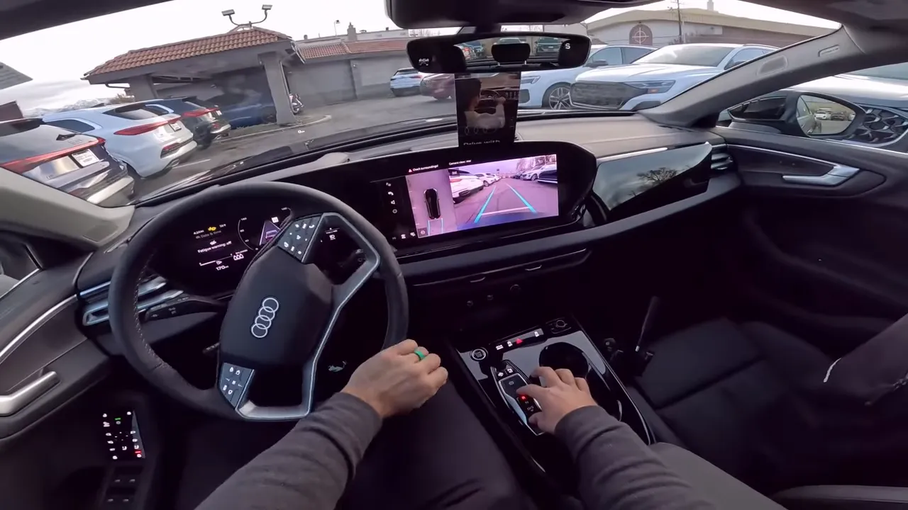 Driver perspective inside 2026 Audi A5 showing digital instrument cluster, large center touchscreen and windshield view