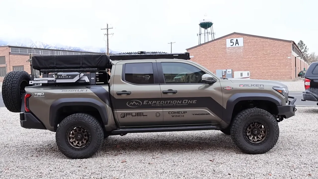 Full side view of Expedition One Tacoma showing swing-out spare, roof rack and integrated bumpers