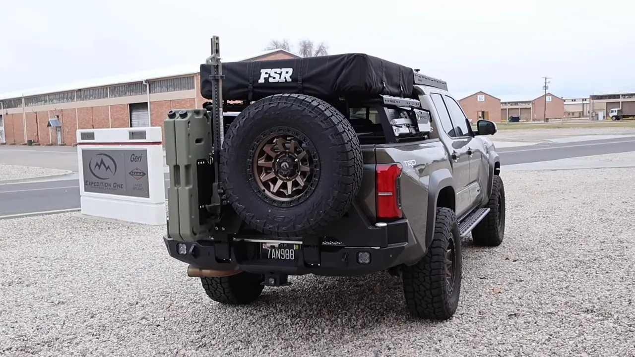 Rear-quarter shot of Tacoma showing spare tire on swing-out mount, jerry can and rooftop tent