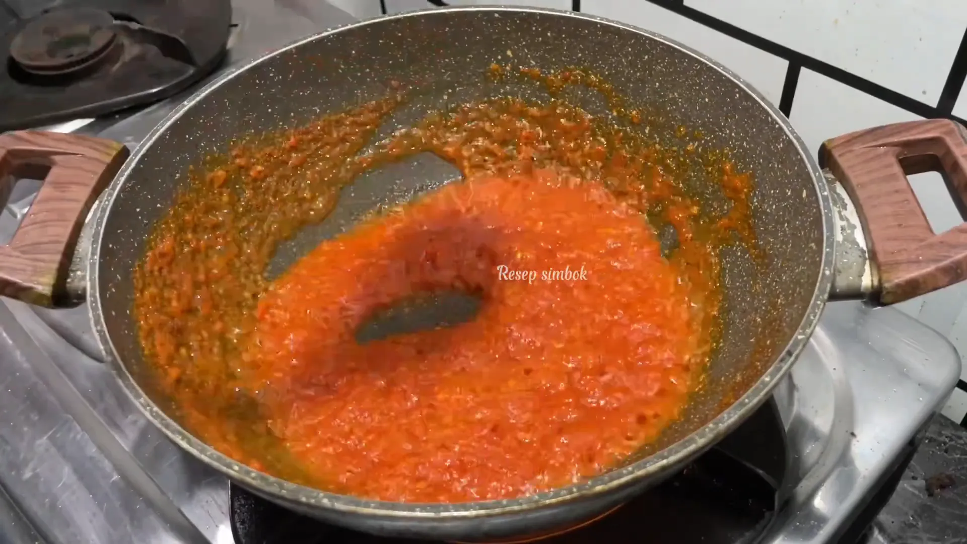 Telur balado sedang dimasak di wajan dengan saus merah pekat