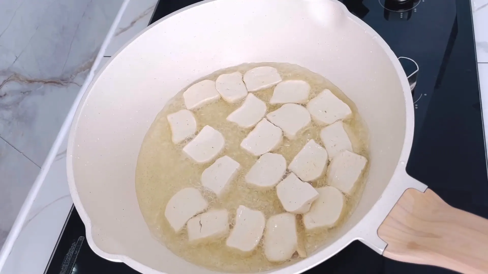 Tahu sedang digoreng hingga bagian bawahnya kecoklatan
