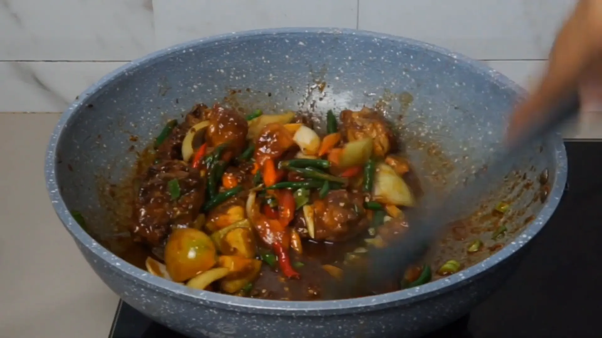 Memasukkan bumbu iris ke dalam masakan ayam asam manis