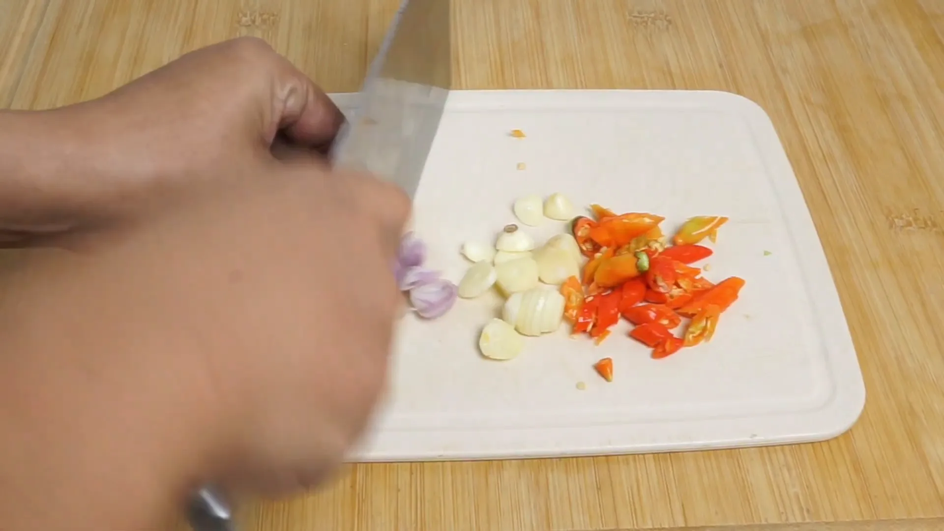 Mengiris bawang merah, bawang putih, dan cabai untuk bumbu