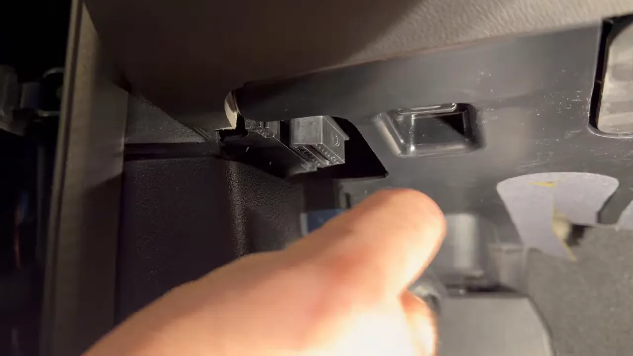 Hand adjusting or inspecting the dash cam power connection near interior trim