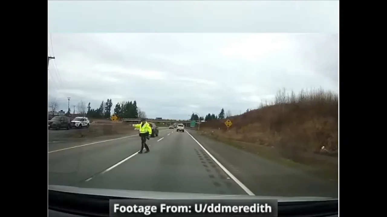 Dash cam footage of highway scene with a police officer in the roadway