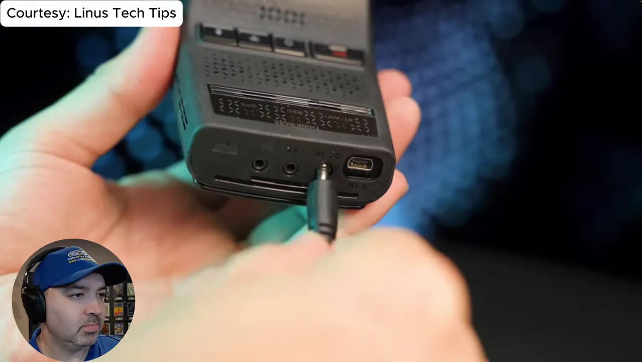 Close-up of a dash-cam style device with a barrel-style power cable plugged into the power port